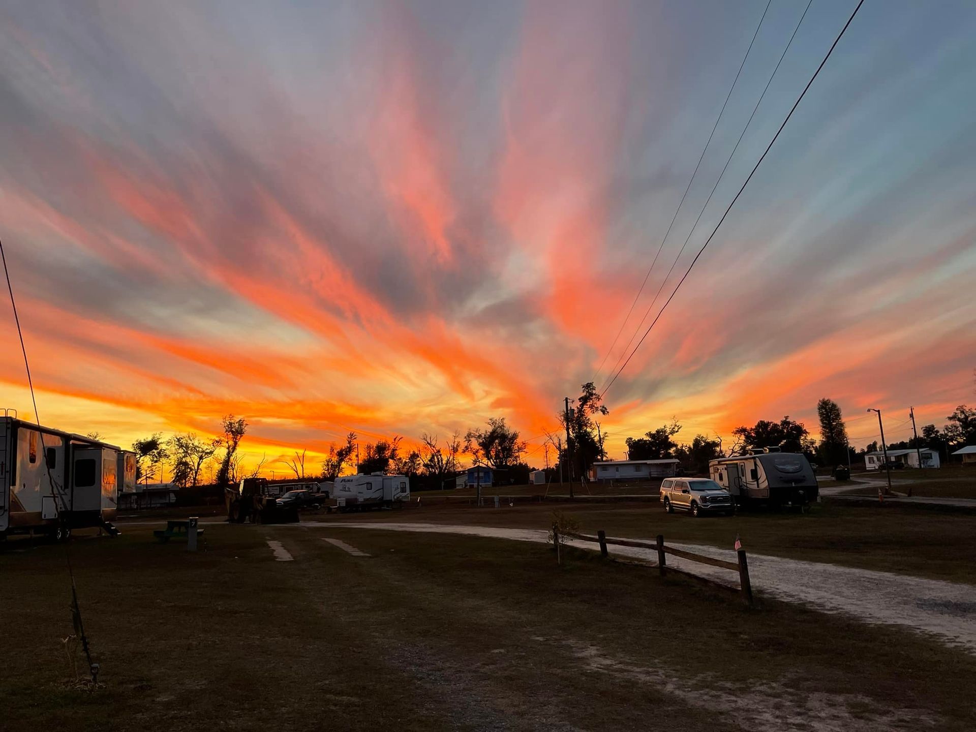 A sunset over a campground with a lot of rvs parked in the background.