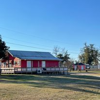 A red house with a blue roof is sitting in the middle of a grassy field.