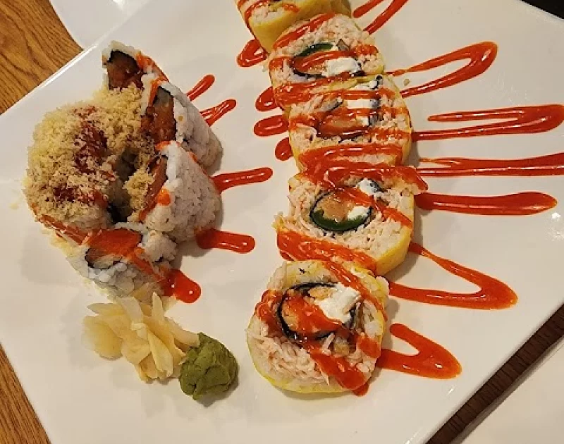 A white plate topped with sushi rolls and sauces