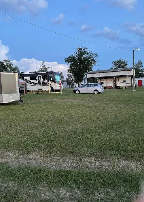 A rv and a car are parked in a grassy field.