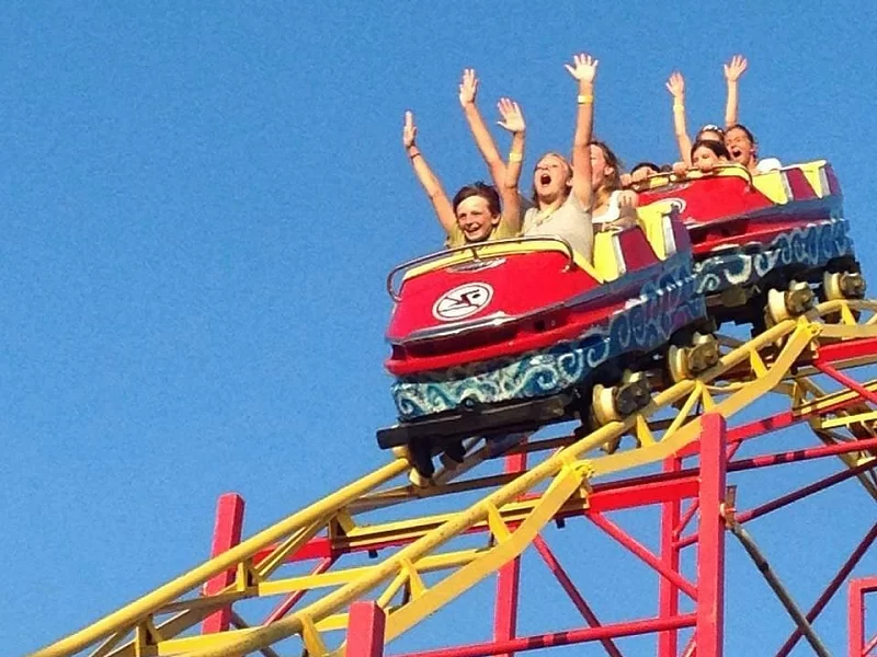 A group of people are riding a roller coaster with their arms in the air