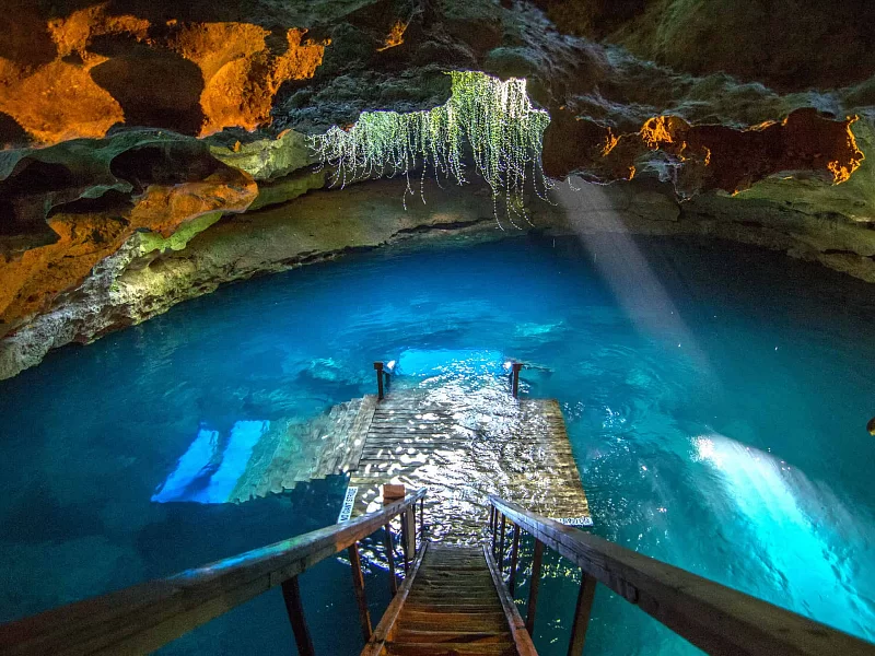 A wooden staircase leading to a large body of water in a cave.