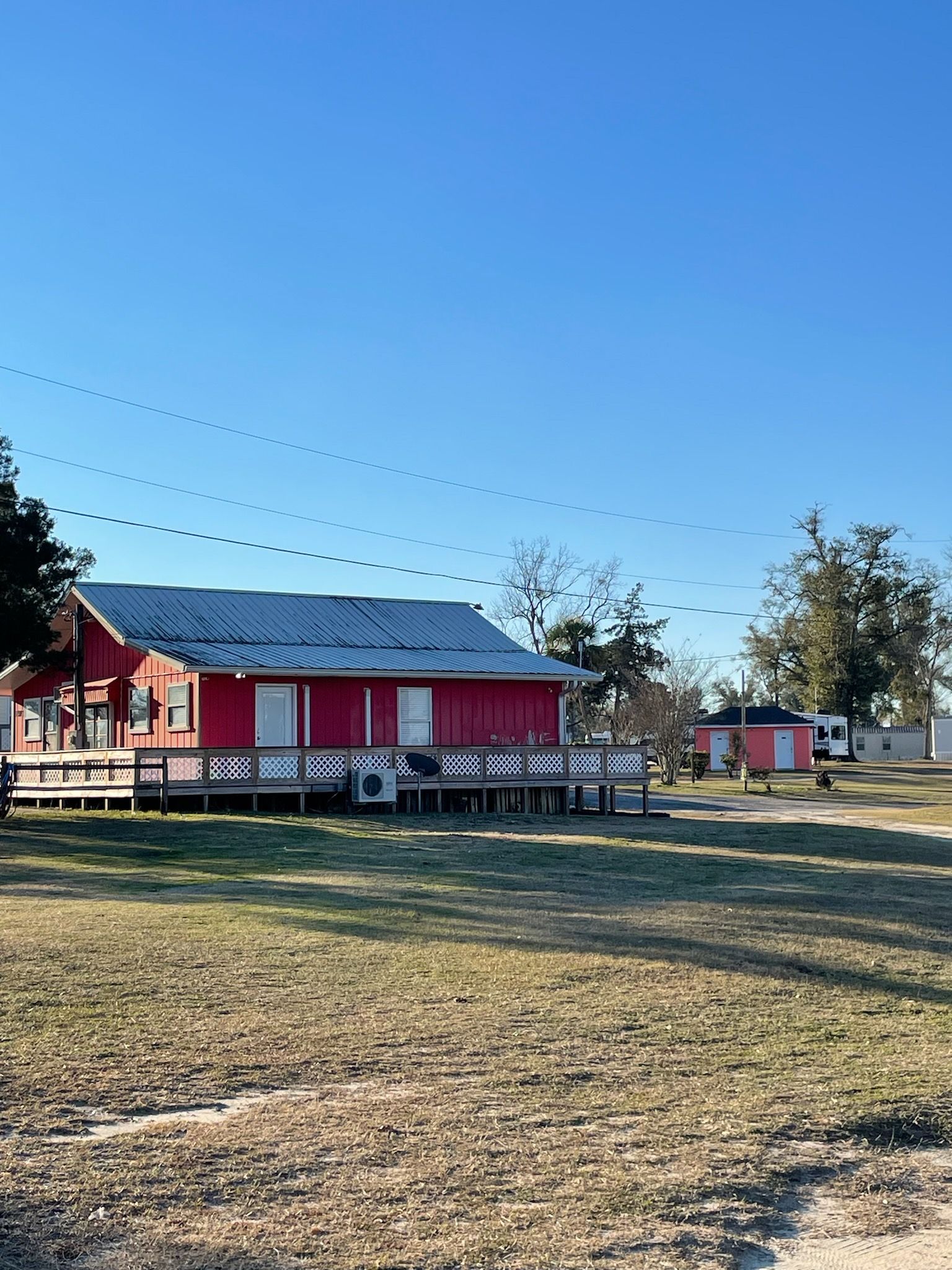 A red house with a blue roof is sitting in the middle of a grassy field.