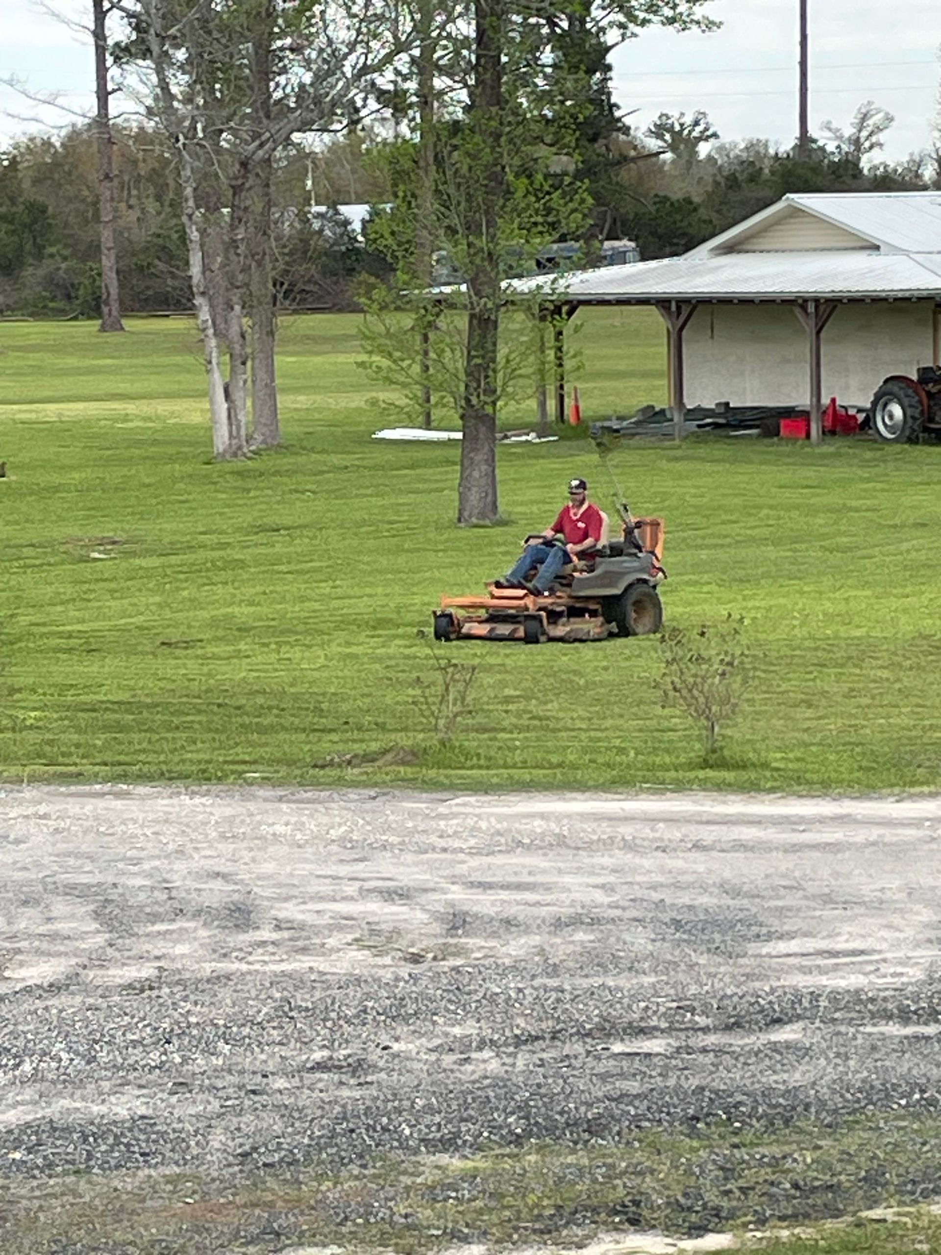 A man is riding a lawn mower in a grassy field.