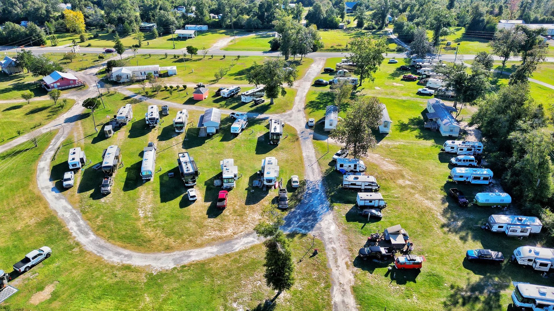 An aerial view of a campground with a lot of rvs parked in the grass.