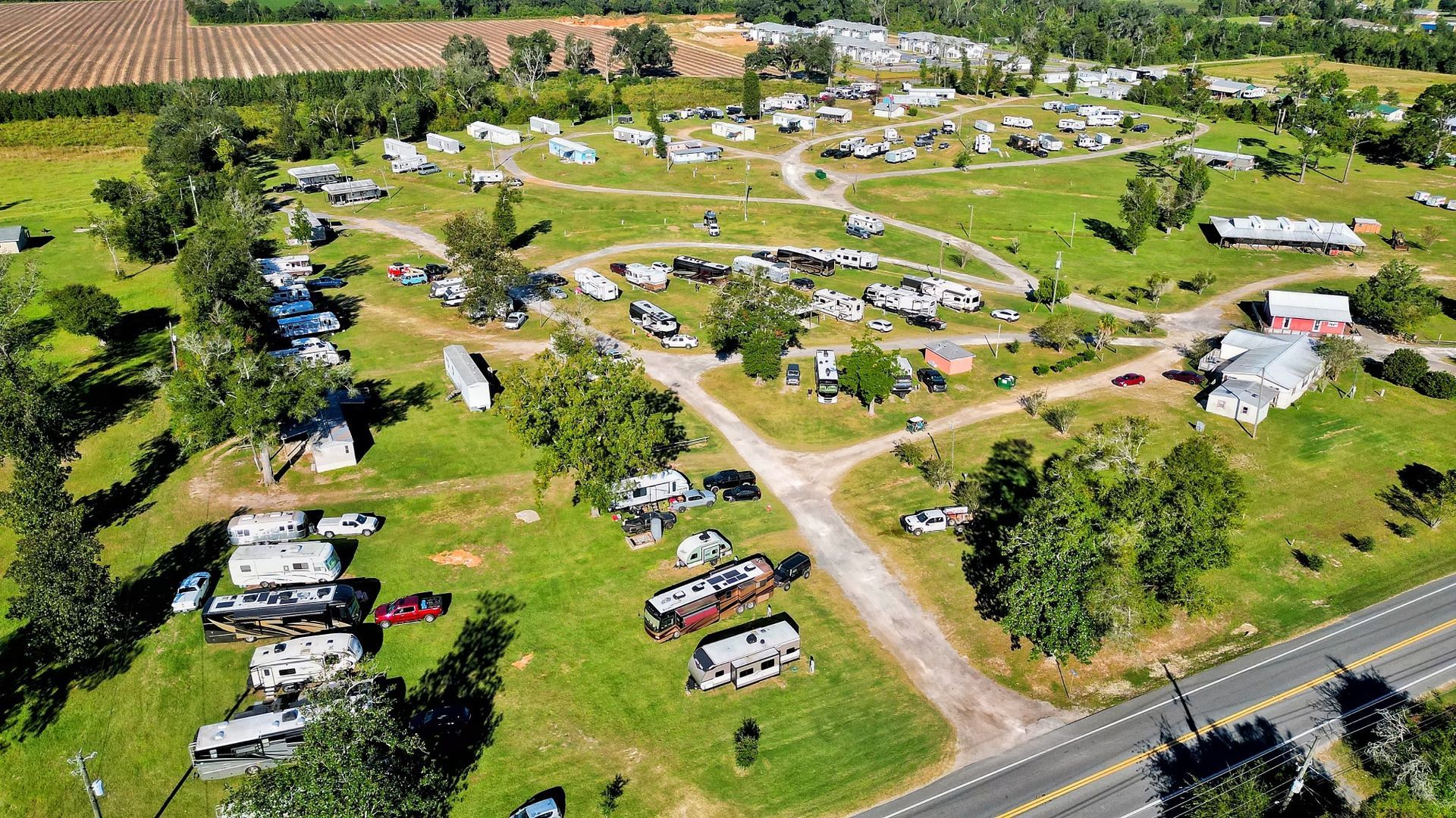 An aerial view of a campground with a lot of vehicles parked in the grass.