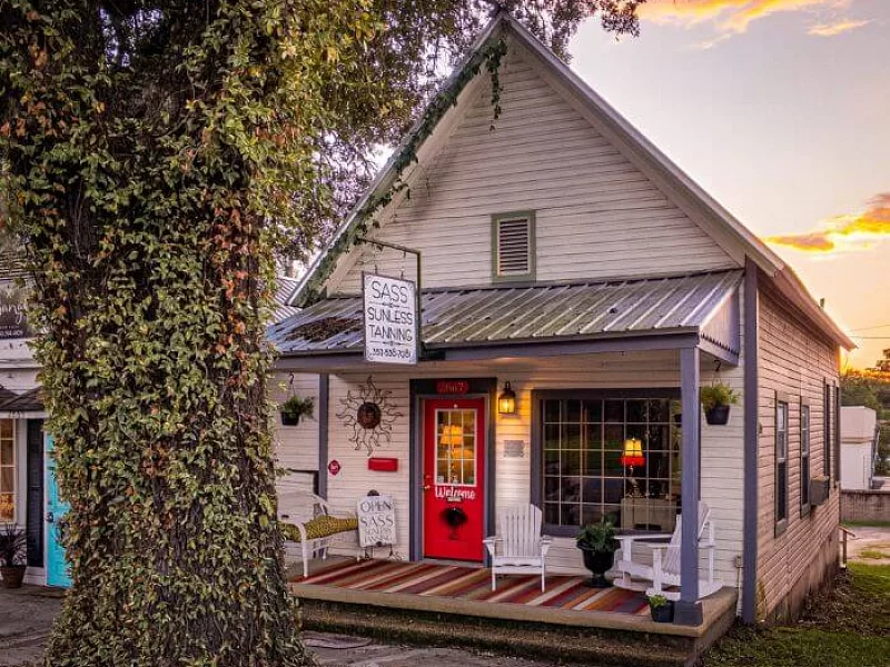 A small white house with a red door and a porch.