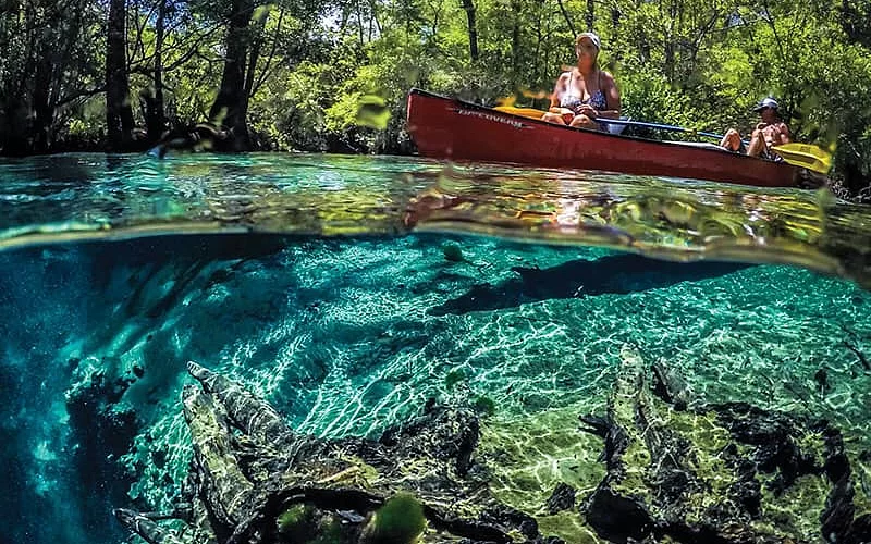 A woman is sitting in a red canoe in a river.