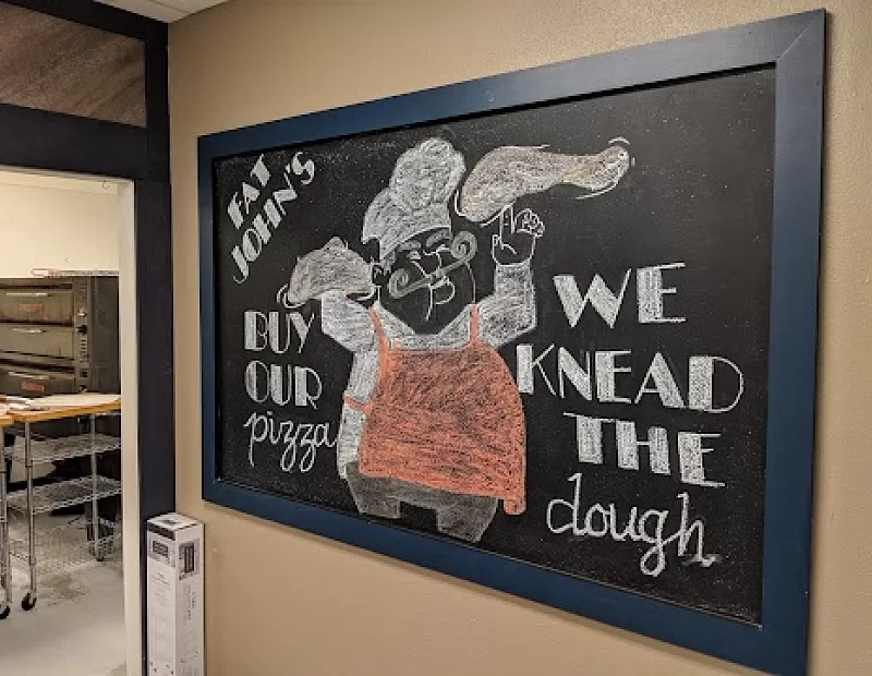 A chalkboard with a picture of a man holding a pizza on it.
