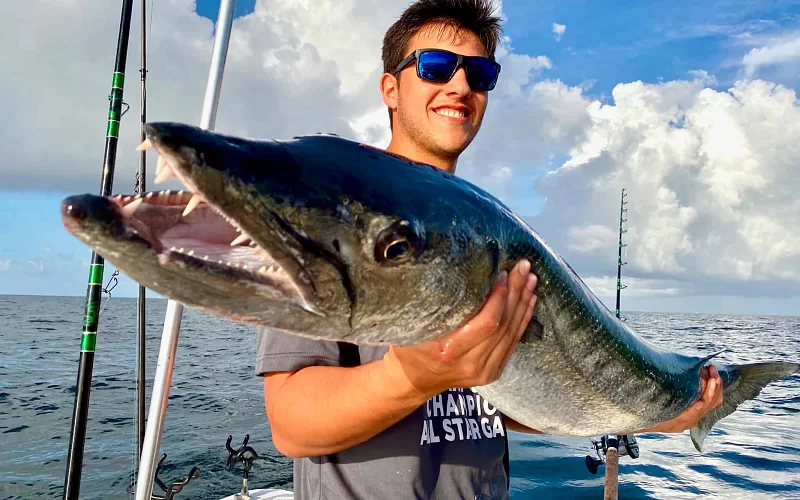 A man is holding a large fish in his hands on a boat.