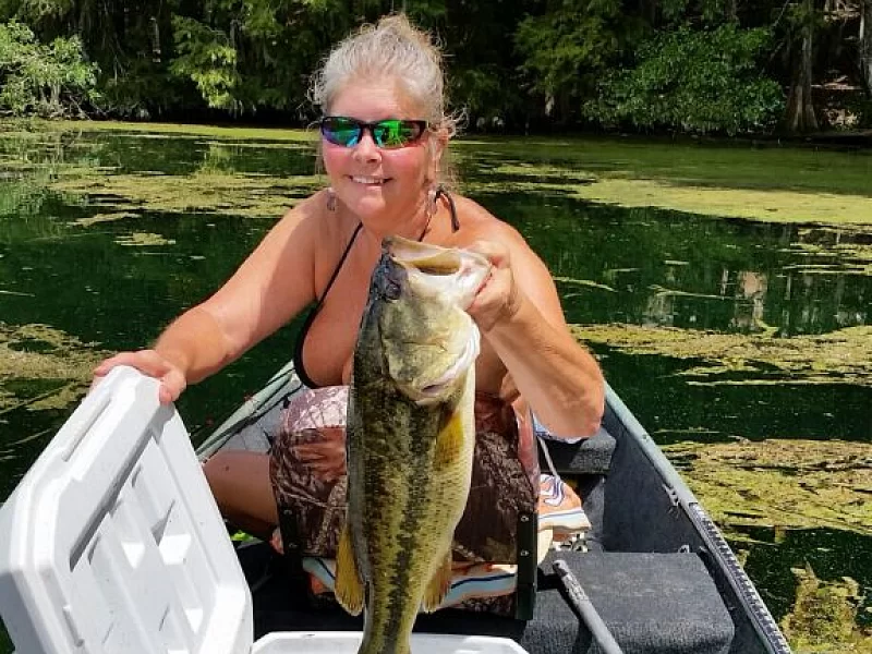 A woman is sitting in a boat holding a large fish