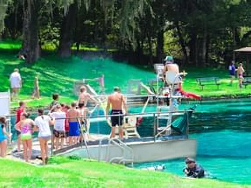 A group of people are standing around a swimming pool.