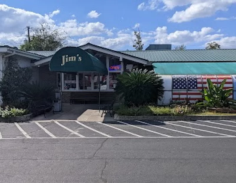 A restaurant with a green awning and an american flag in front of it.