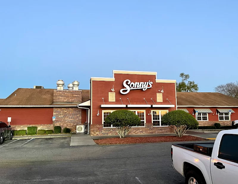 A white truck is parked in front of a sonny 's restaurant.