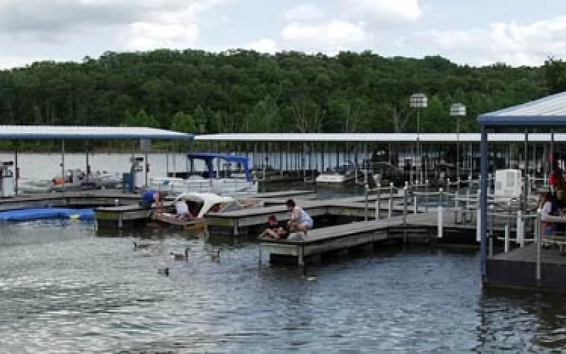 A group of people are sitting on a dock at a marina.