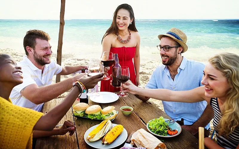 A group of people are sitting at a table eating food and drinking wine.