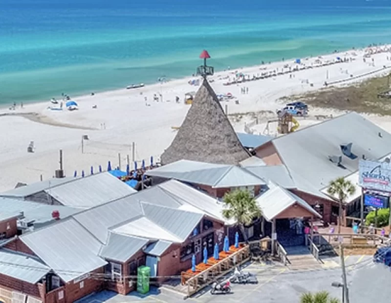 An aerial view of a restaurant on a beach next to the ocean.