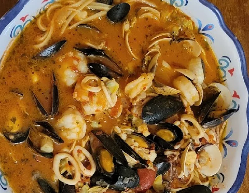 A bowl of seafood soup with noodles and mussels