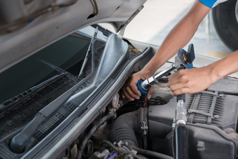 A Man is Working on the Engine of a Car With the Hood Open — Fosters Ace Auto Repairs In Aitkenvale, QLD