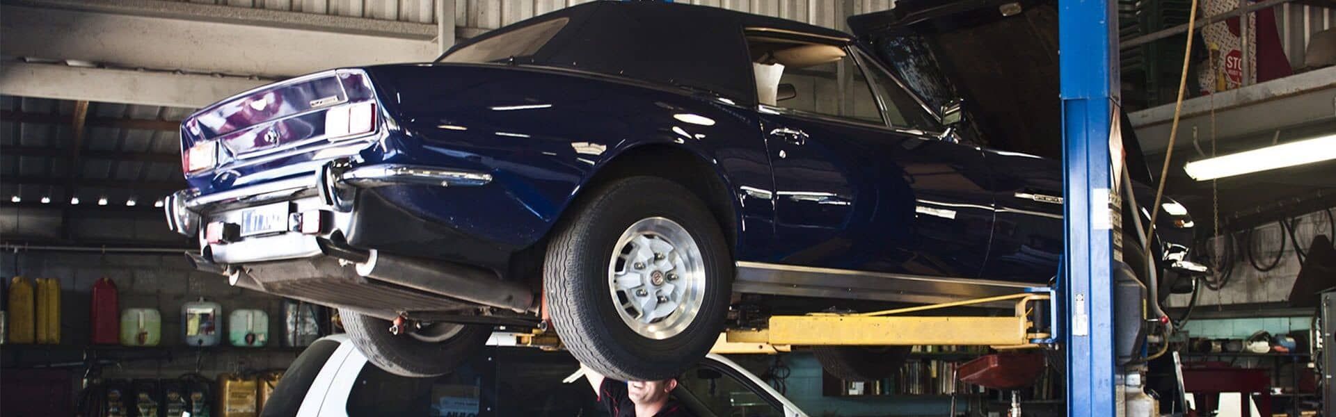 A Blue Car is Sitting on a Lift in a Garage — Fosters Ace Auto Repairs In Aitkenvale, QLD