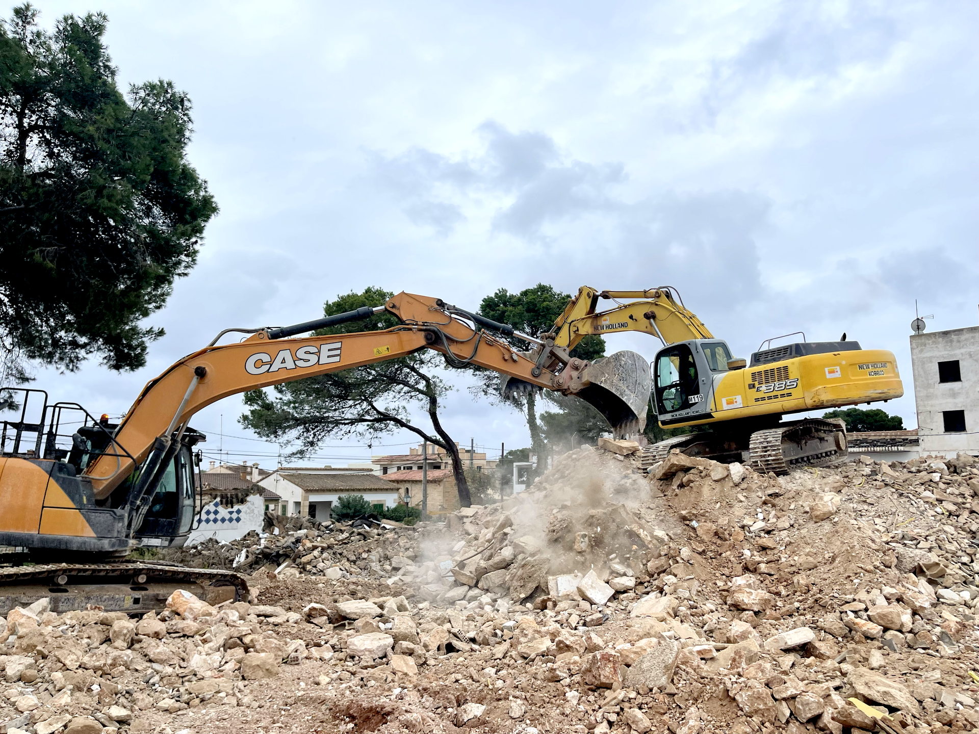 Dos excavadoras de construcción CAN RAMIS demoliendo un edificio en un día nublado.