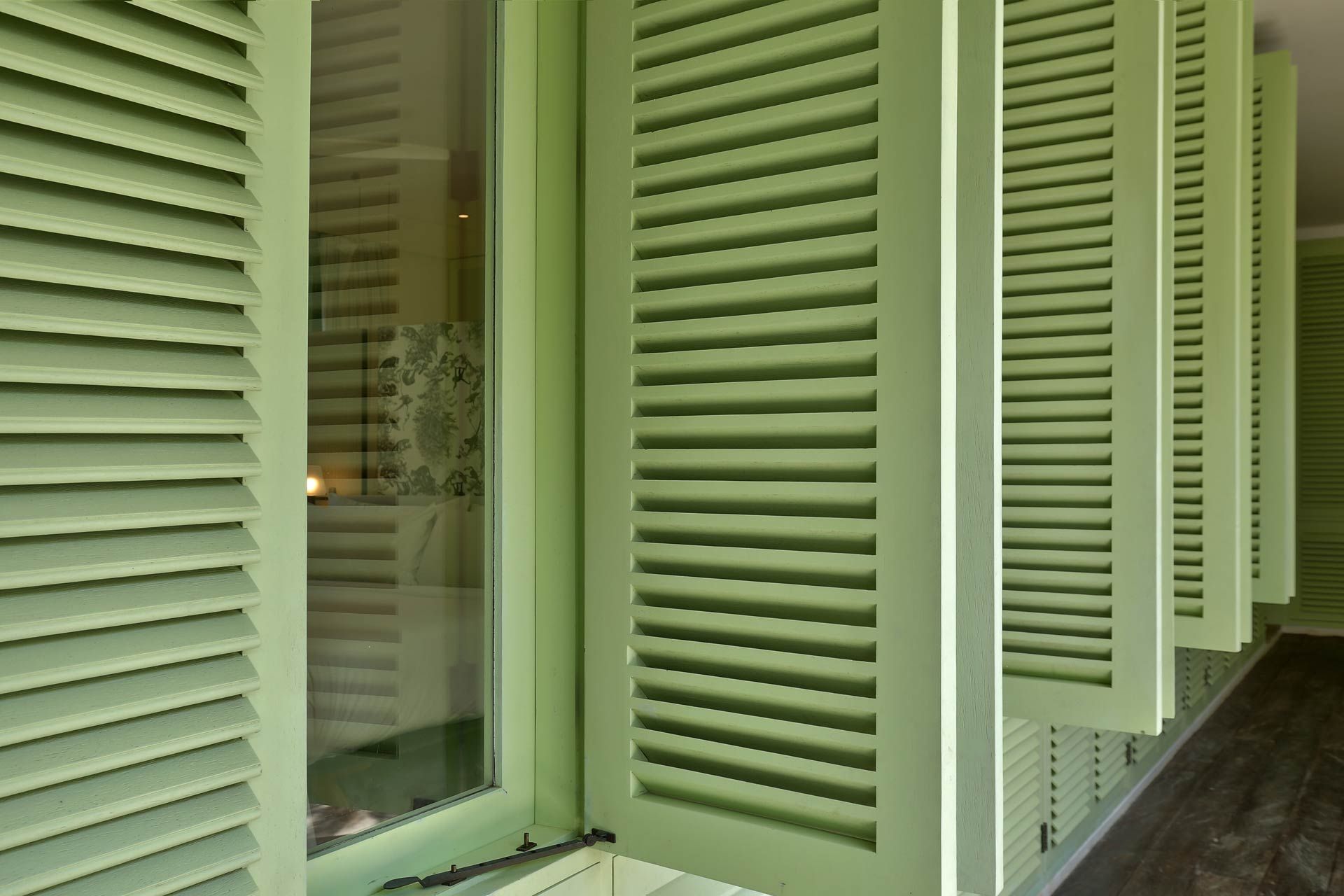 A row of green shutters on a window in a room