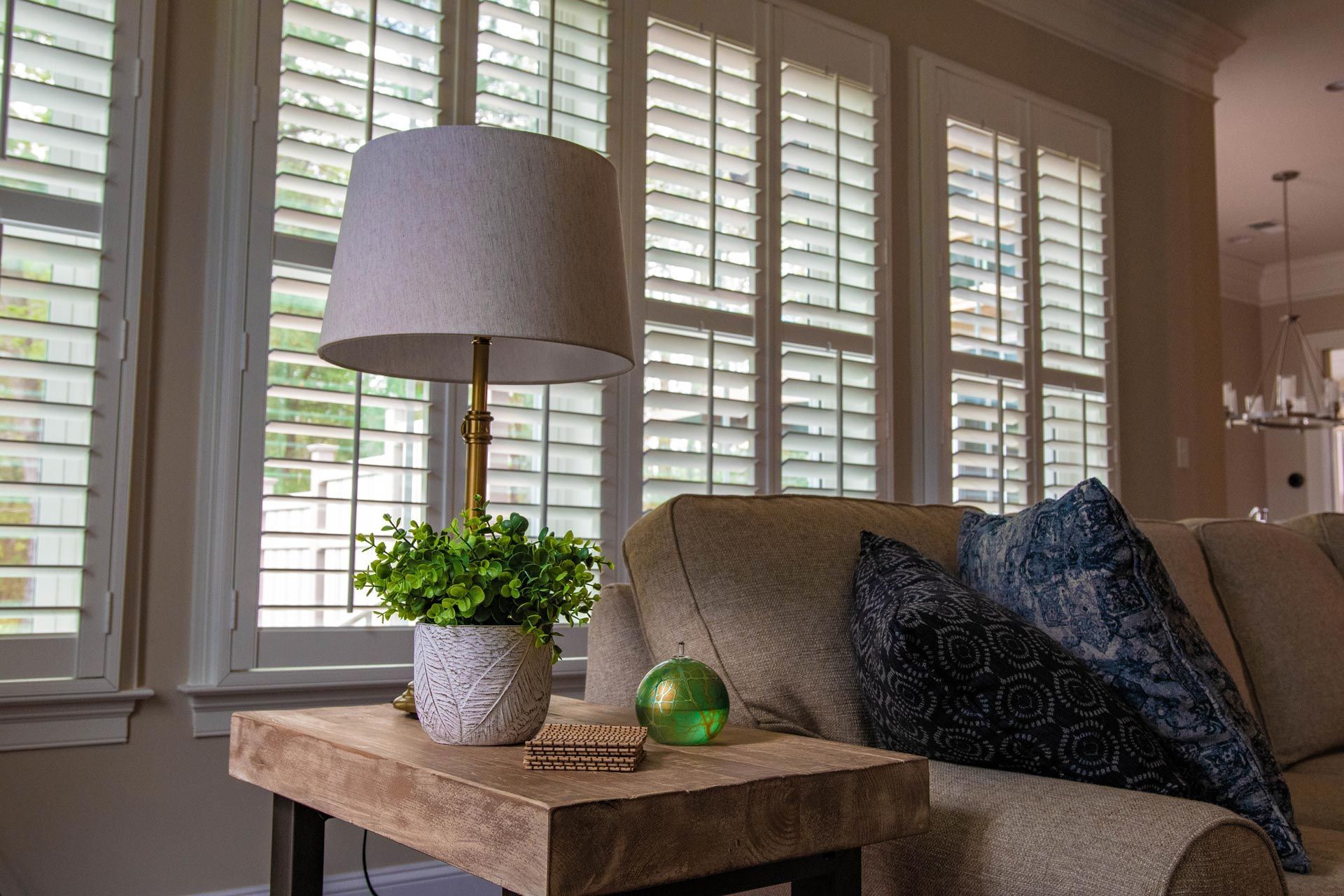 A living room with a couch , table , lamp and shutters.