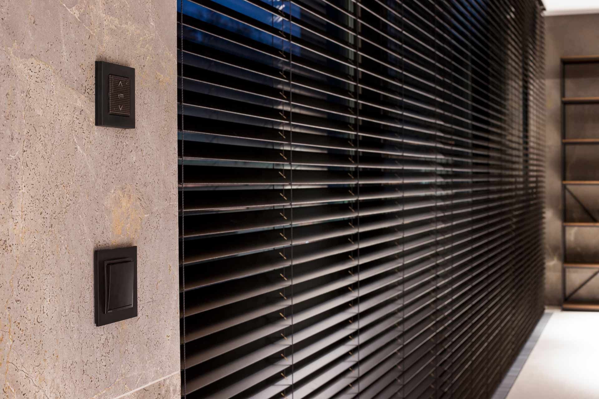 A wall with shutters and a light switch on it