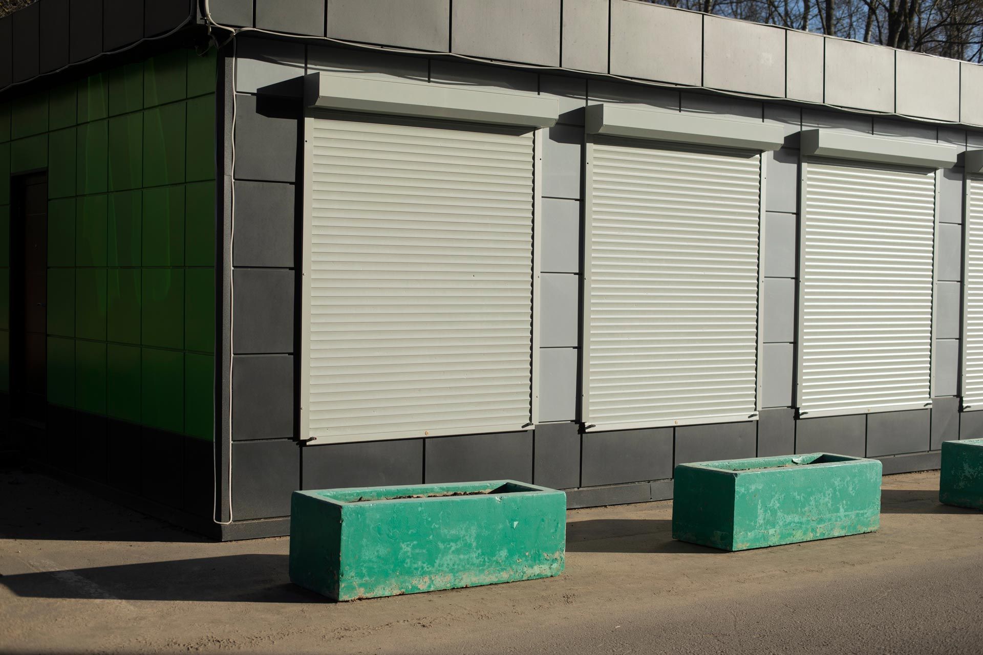 A green building with white shutters on the windows