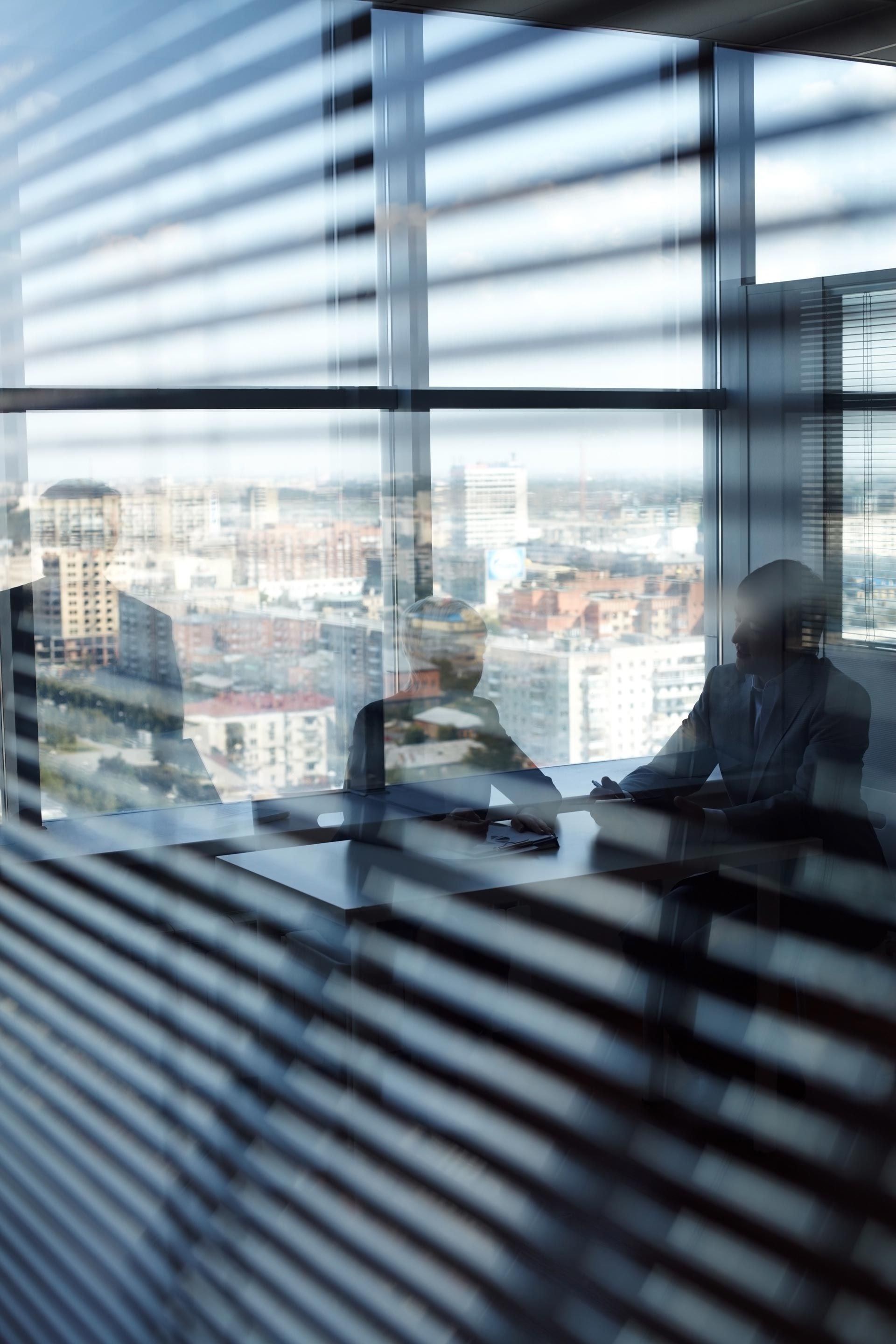 A group of people are sitting at a table in front of a window