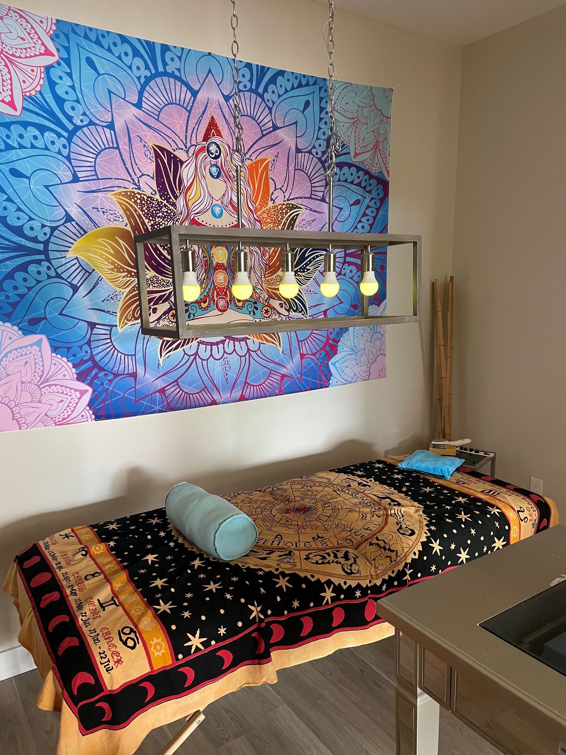 A massage table in a room with a tapestry on the wall.