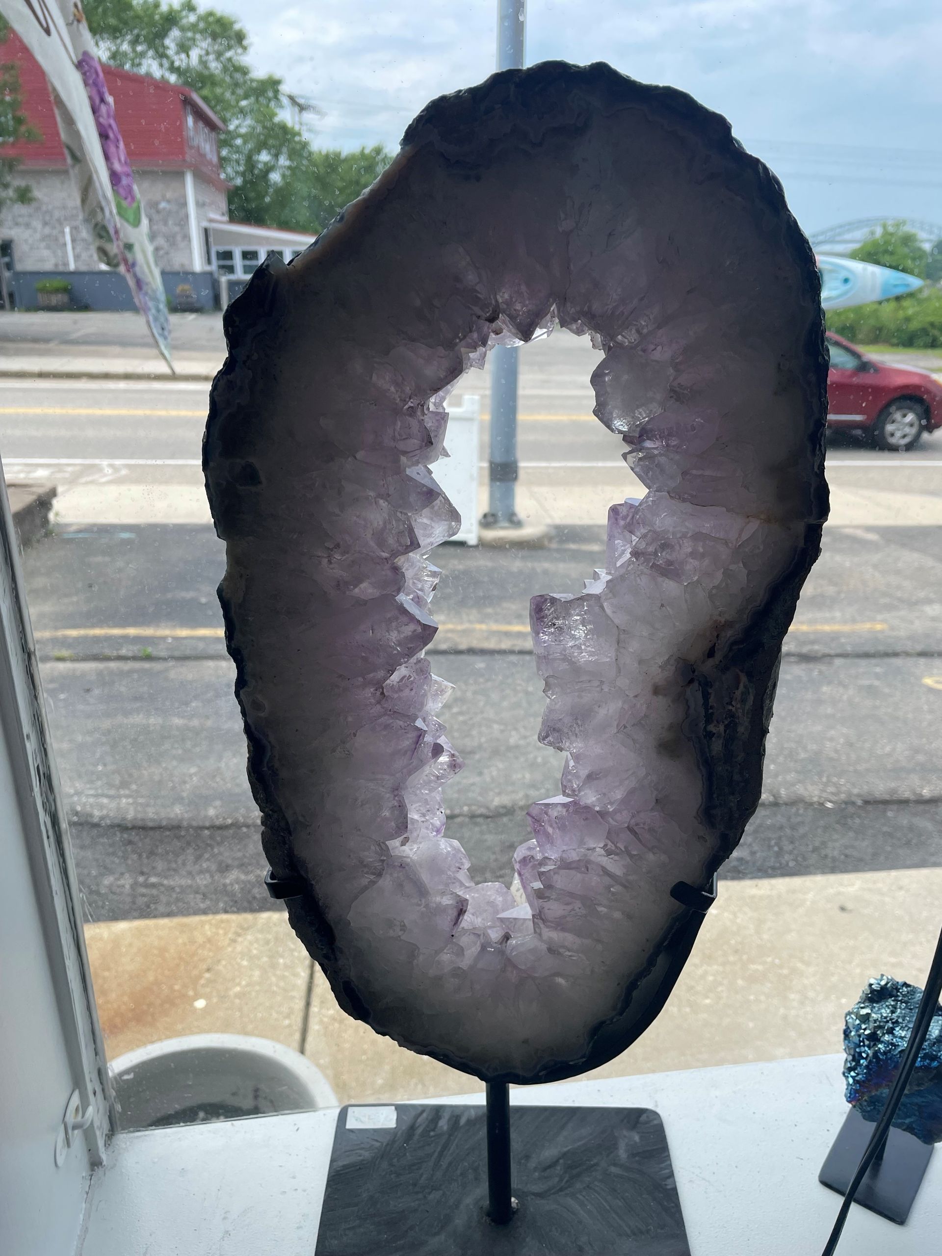 A large piece of amethyst is sitting on a table in front of a window.