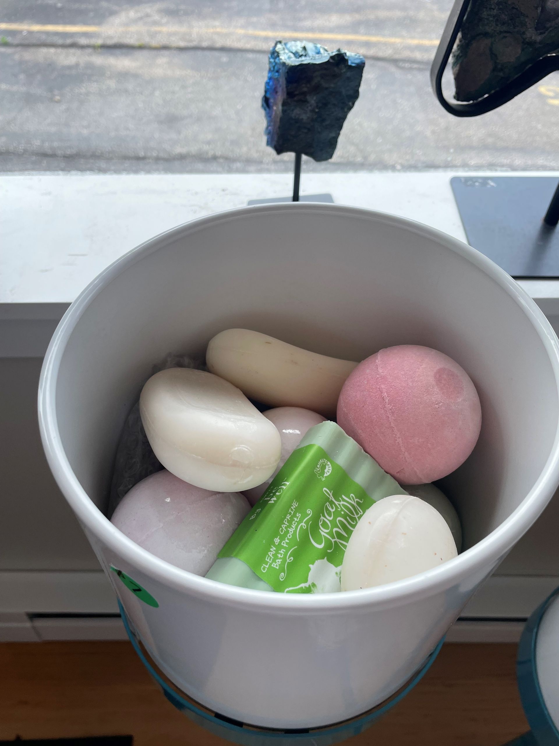 A white bucket filled with different types of soaps