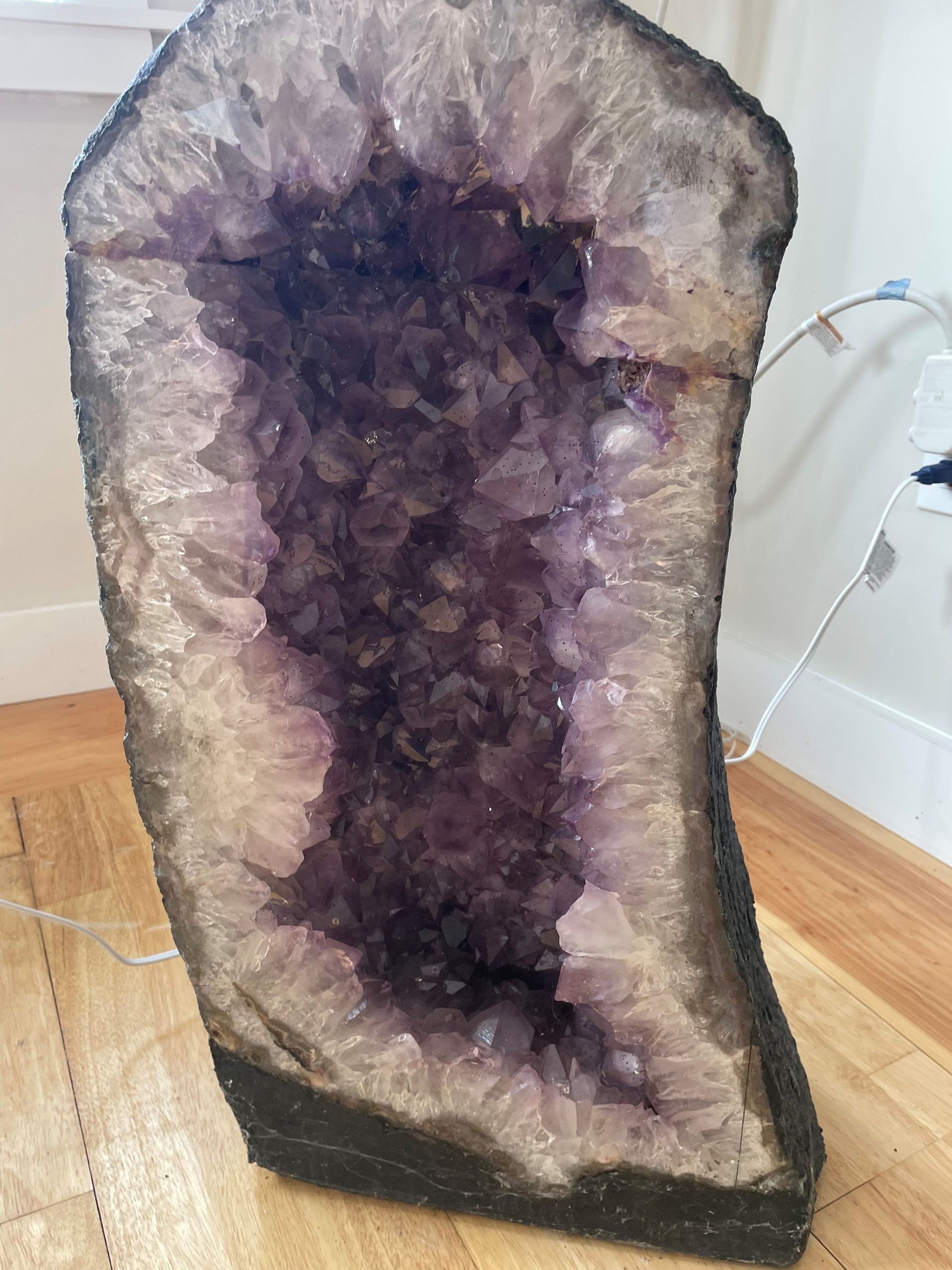 A large piece of amethyst is sitting on a wooden floor