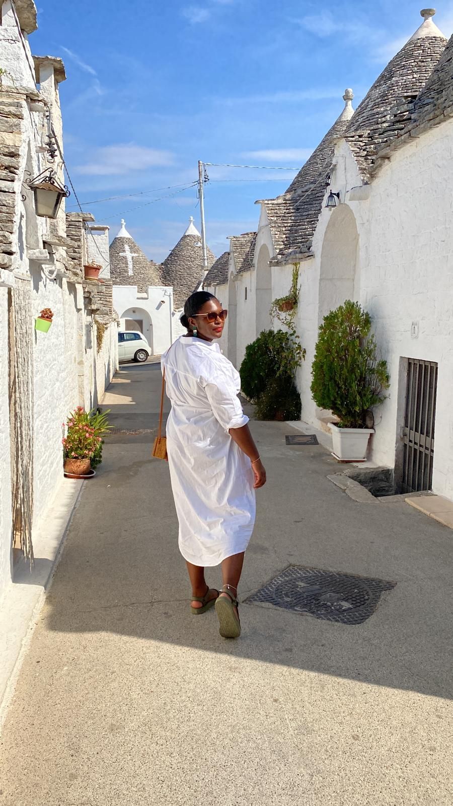 A woman in a white dress is walking down a narrow street.