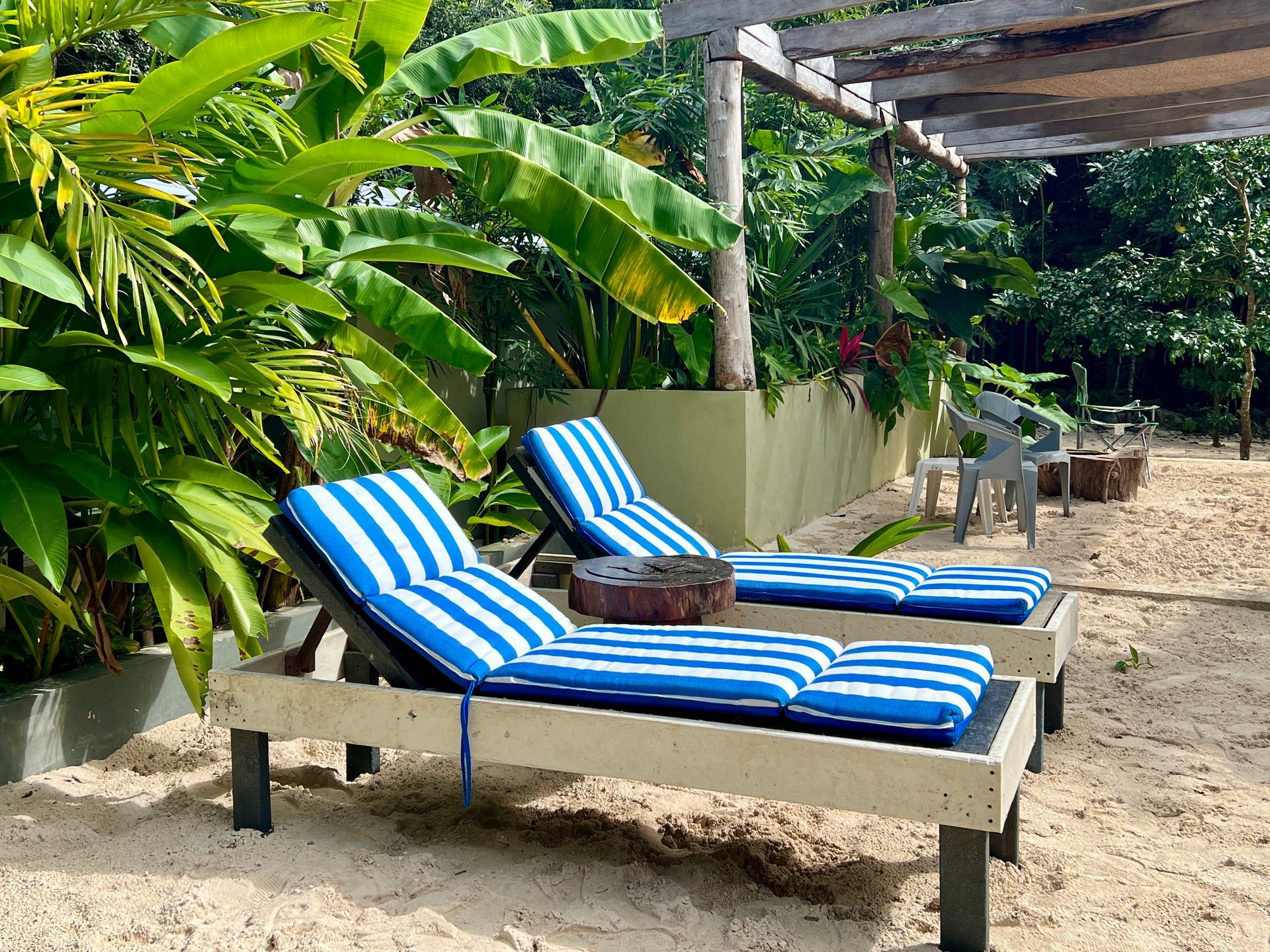 Two blue and white striped lounge chairs on a sandy beach