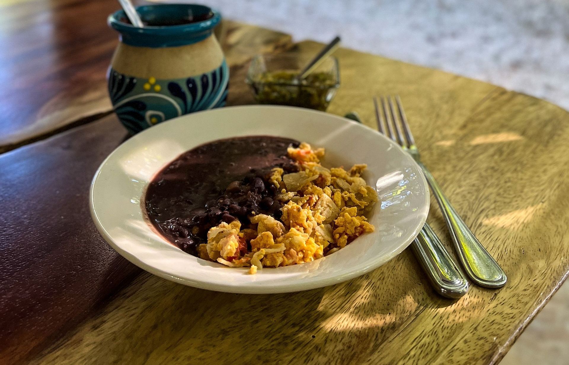 A plate of food with beans and rice on a wooden table.
