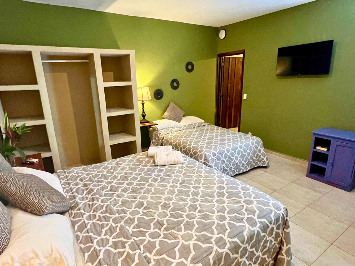 A hotel room with two beds, a closet, and a flat screen tv.