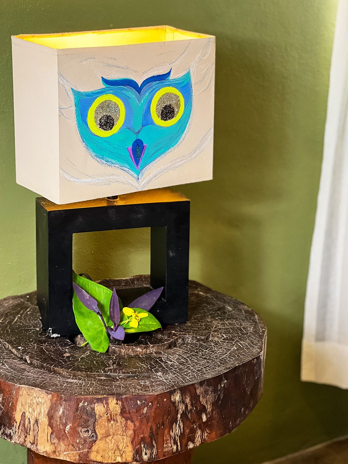 A lamp with an owl on it is sitting on a wooden table