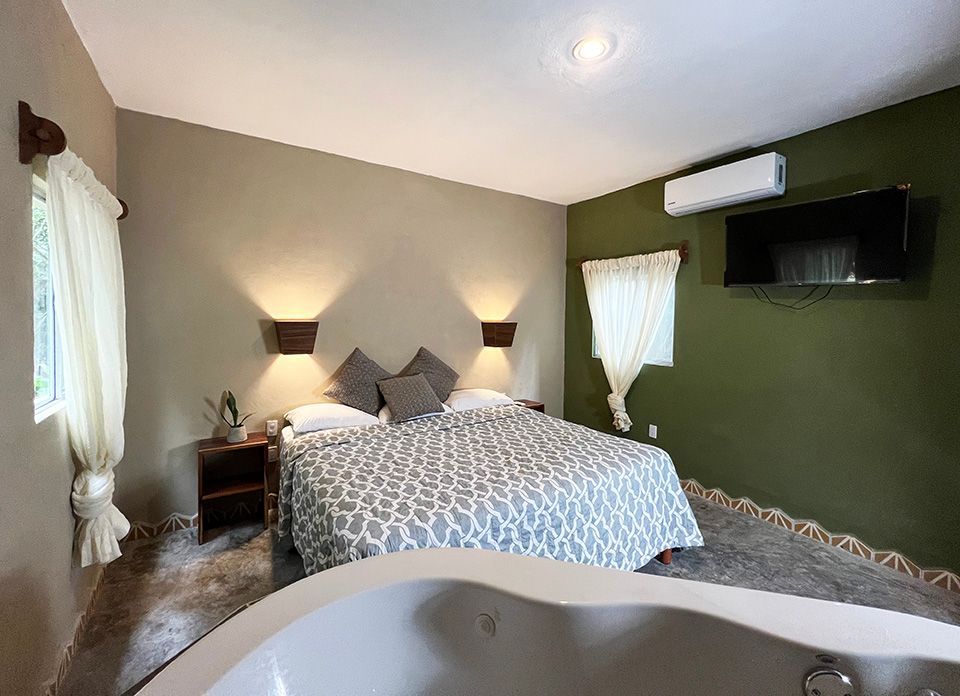 A hotel suite with a king size bed and a jacuzzi tub.