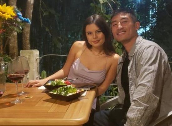 A man and a woman are sitting at a table with bowls of food and wine glasses