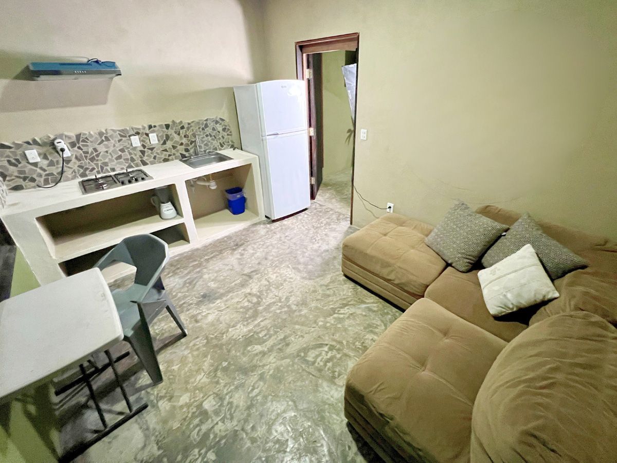 A living room with a couch , table , chairs and a refrigerator.