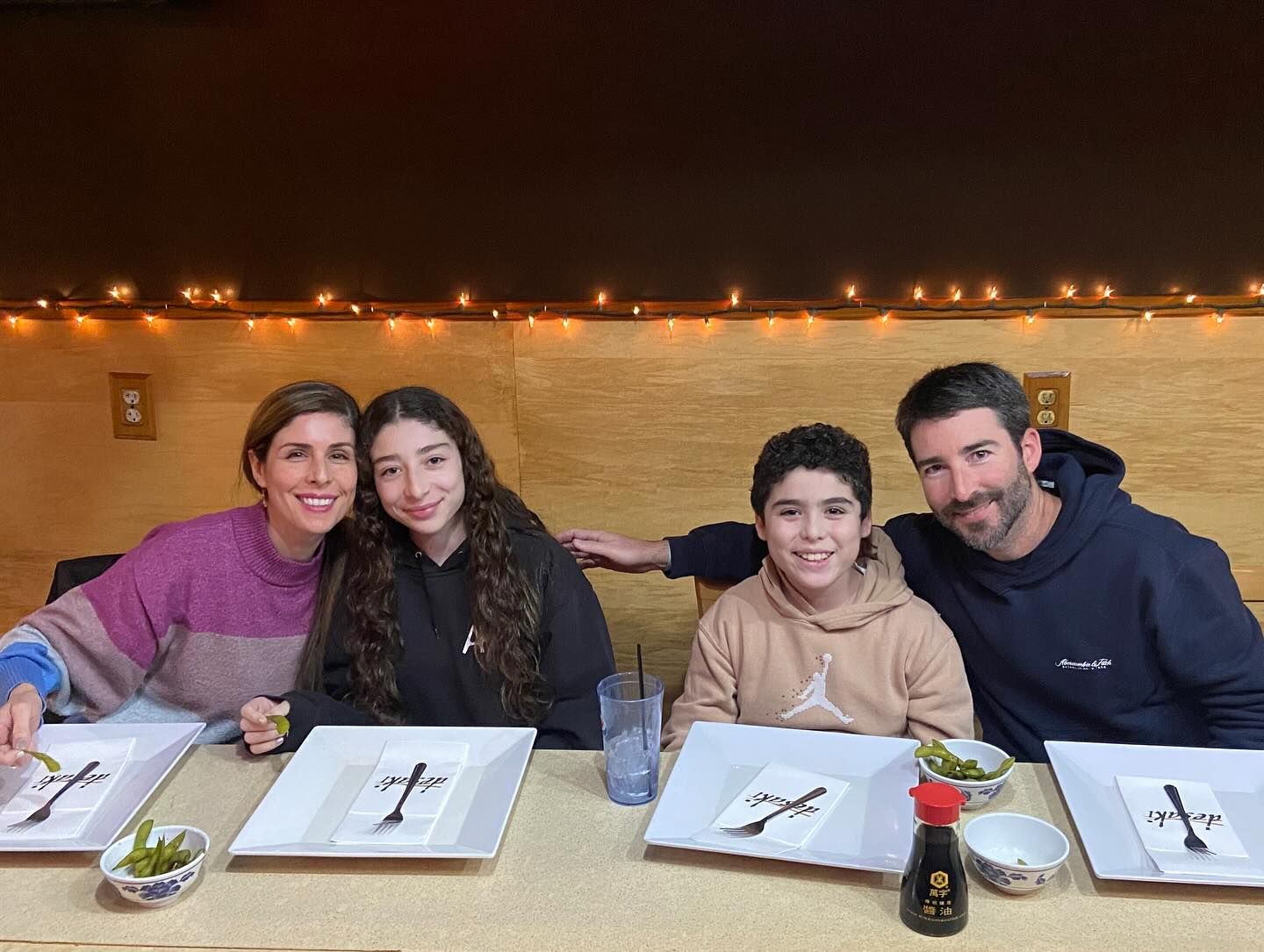 A family is sitting at a table with plates ready for food at desaki