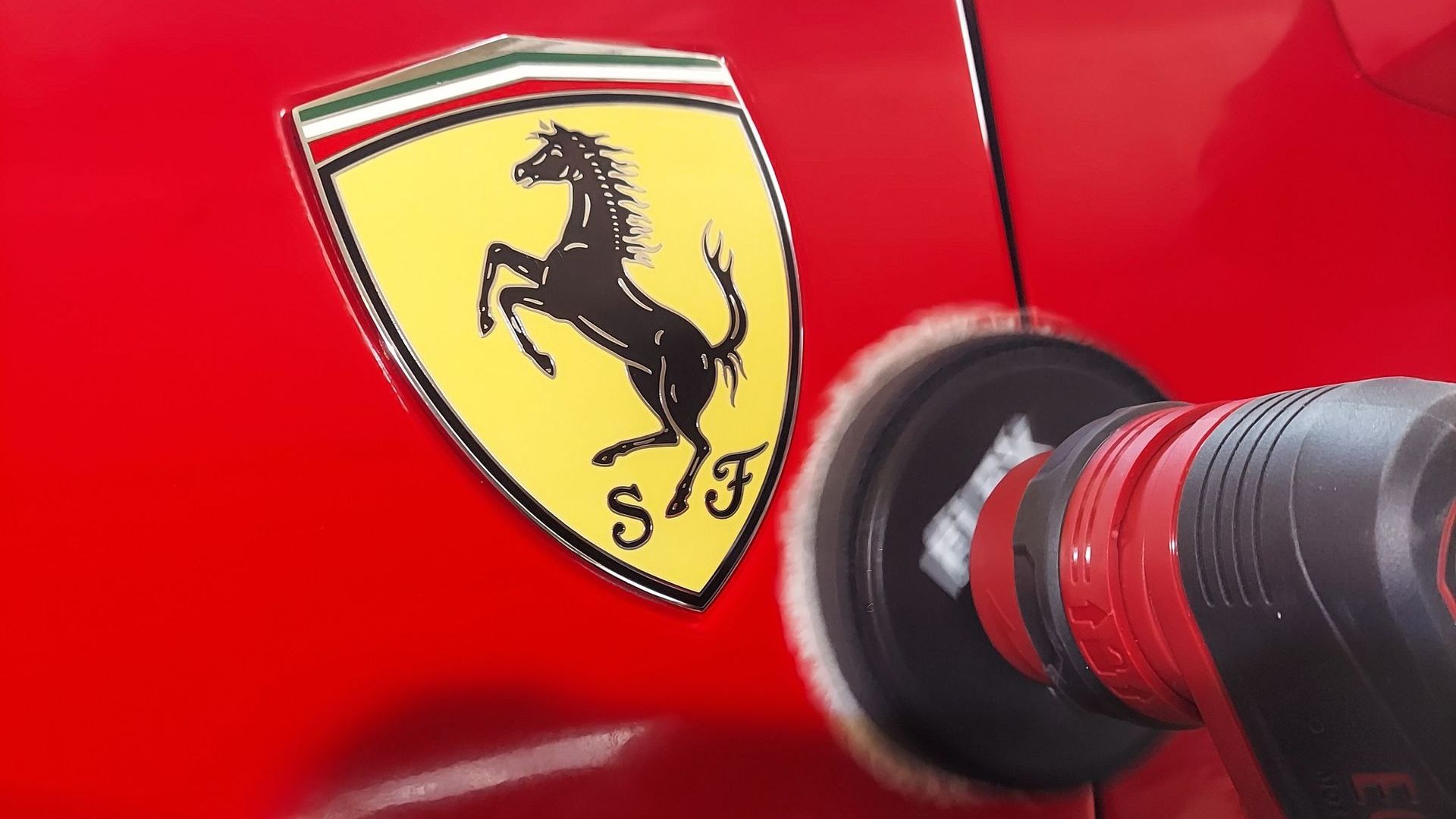 A ferrari logo is being polished on a red car.