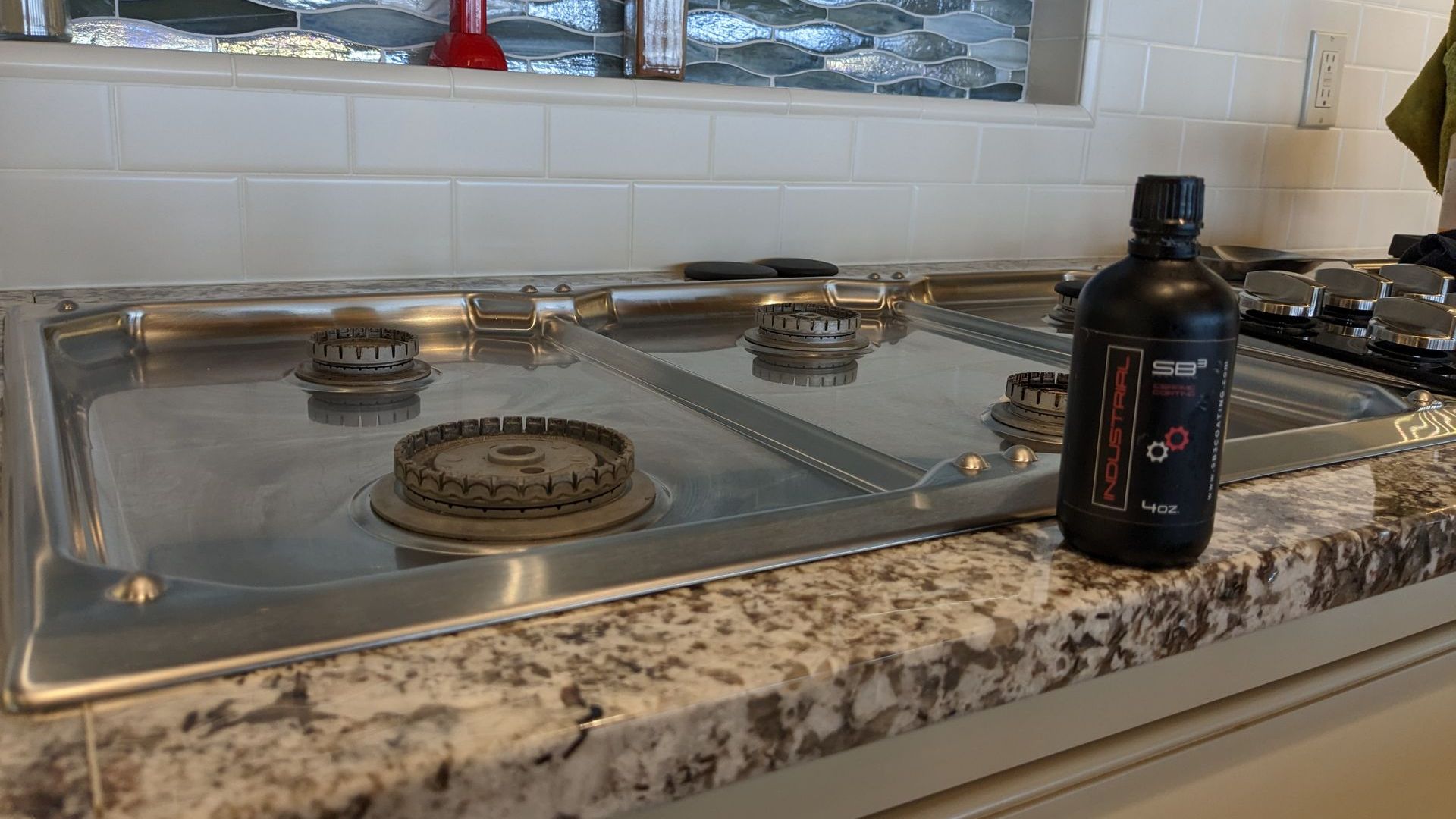 A bottle of oil is sitting on a kitchen counter next to a gas stove.