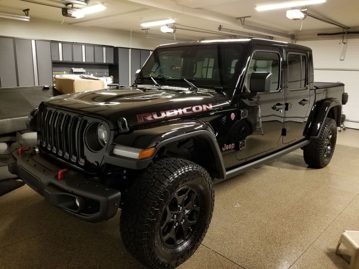 A black jeep wrangler rubicon is parked in a garage.