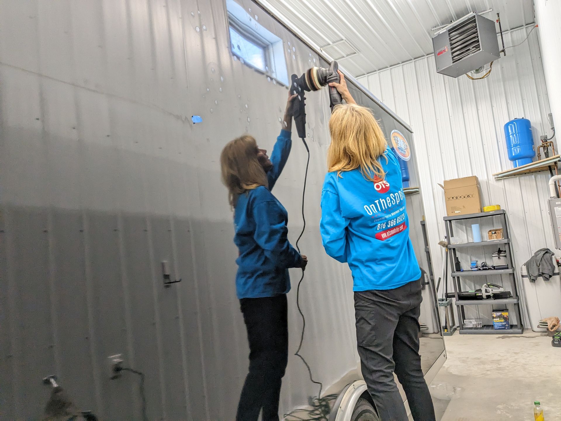 Two women are working on a wall in a garage.