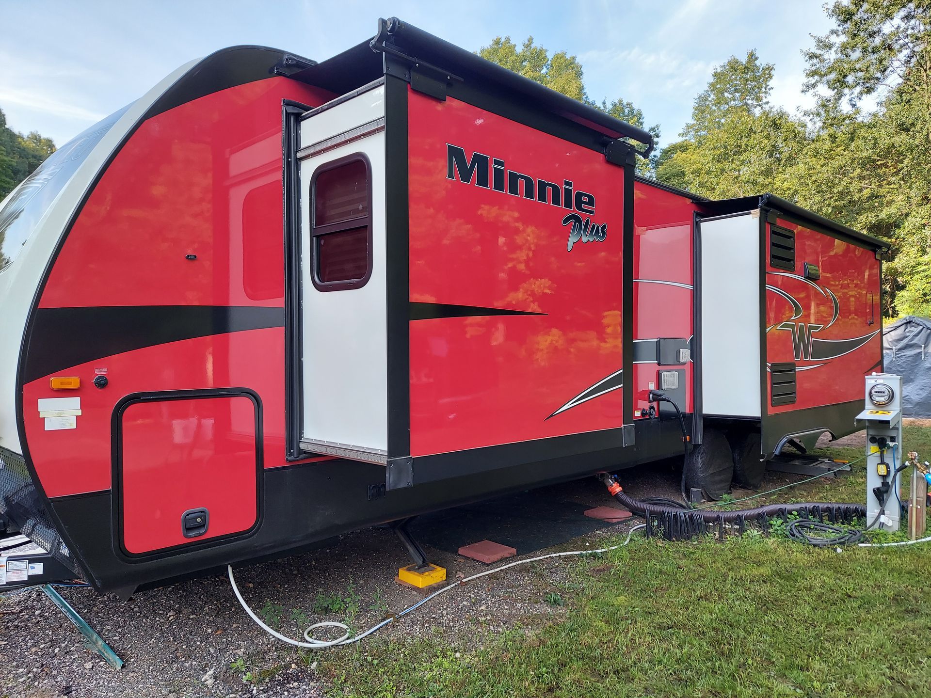 A red and black rv is parked in a grassy area.