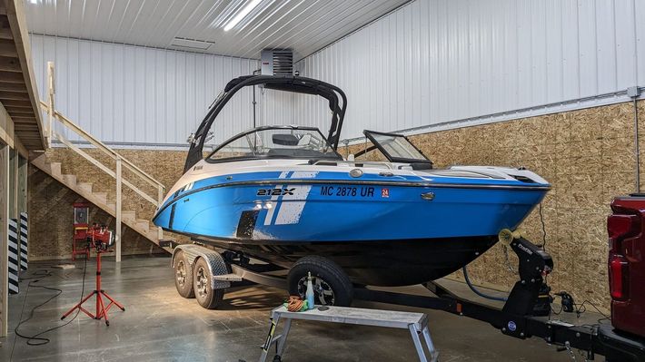 A blue and white boat is parked in a garage.