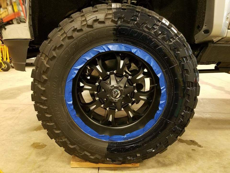 A black tire with a blue rim is sitting on a wooden table.